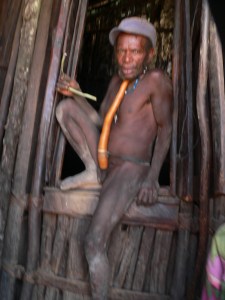 Ekari man smoking. In this region tobacco is smoked through a plant stem.
